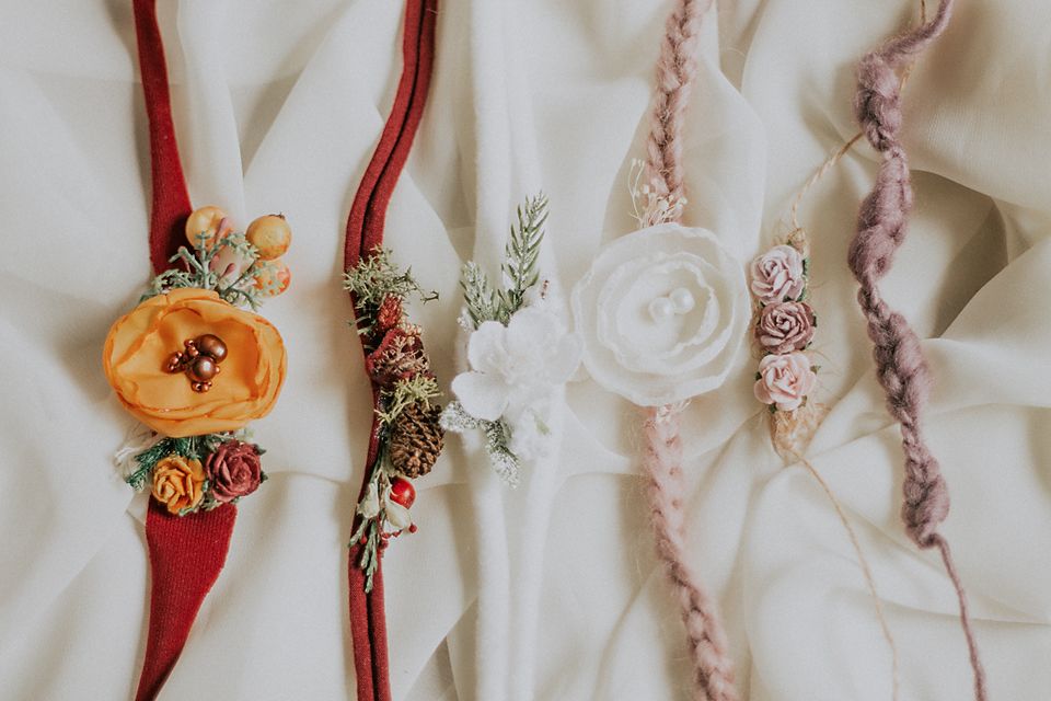 Decorative floral arrangements with red ribbons and delicate pink and yellow flowers on white fabric.