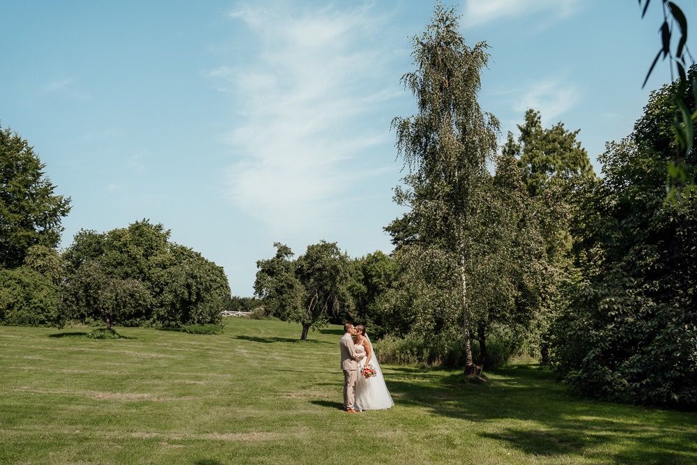 A couple celebrates their wedding day on a lush green golf course surrounded by trees and natural scenery.