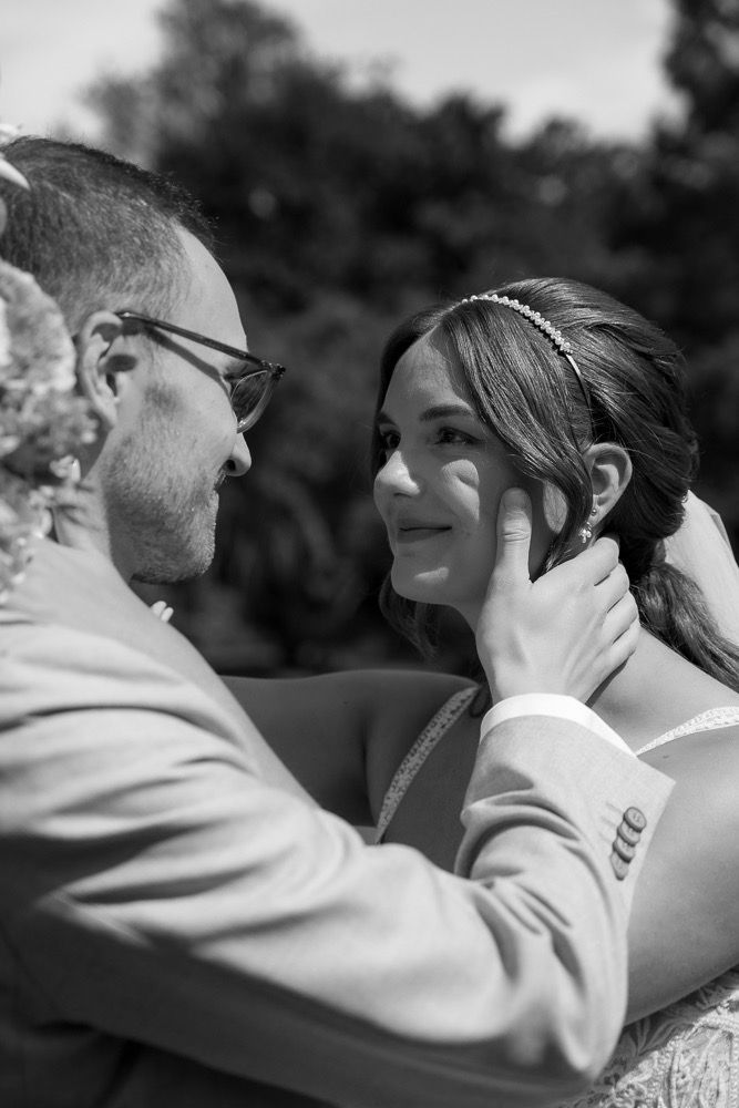 A tender black and white wedding moment captured outdoors as a couple shares an intimate embrace.