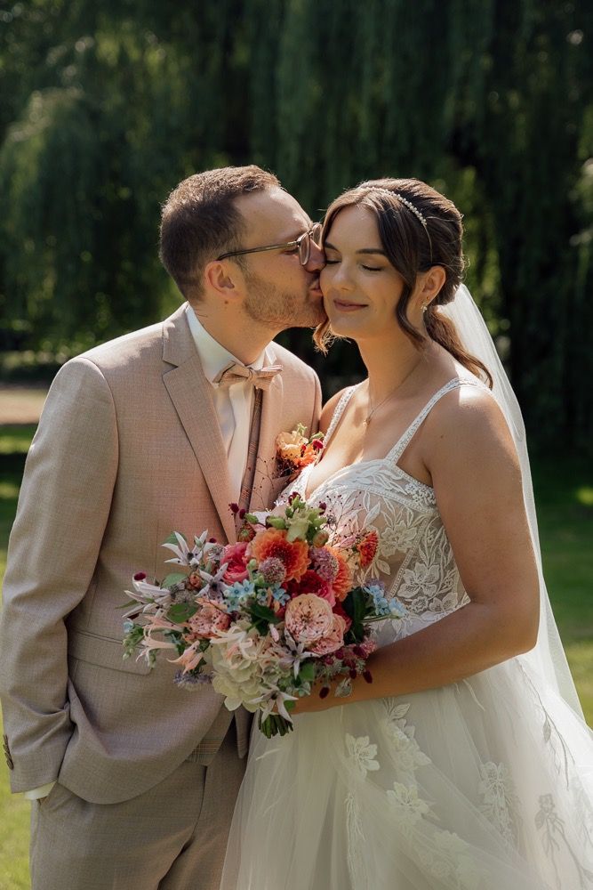 Intimate wedding portraits show tender moments between newlyweds against a lush garden landscape.