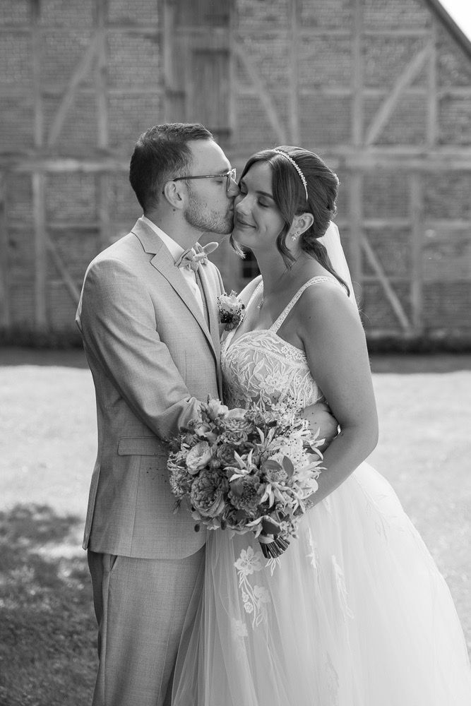 A romantic wedding couple shares intimate moments in black and white photos while holding a floral bouquet.