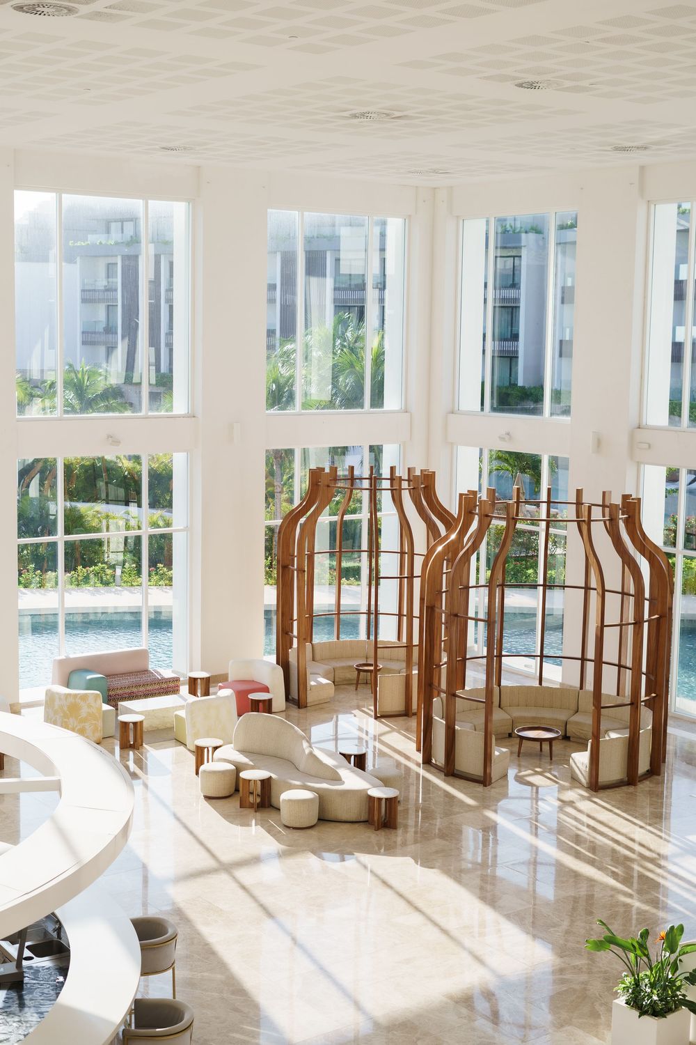 Modern spa-like interior space with wooden columns and white furnishings bathed in natural sunlight.