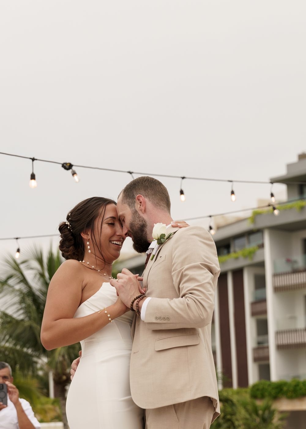 Romantic moment under string lights at a tropical resort venue.