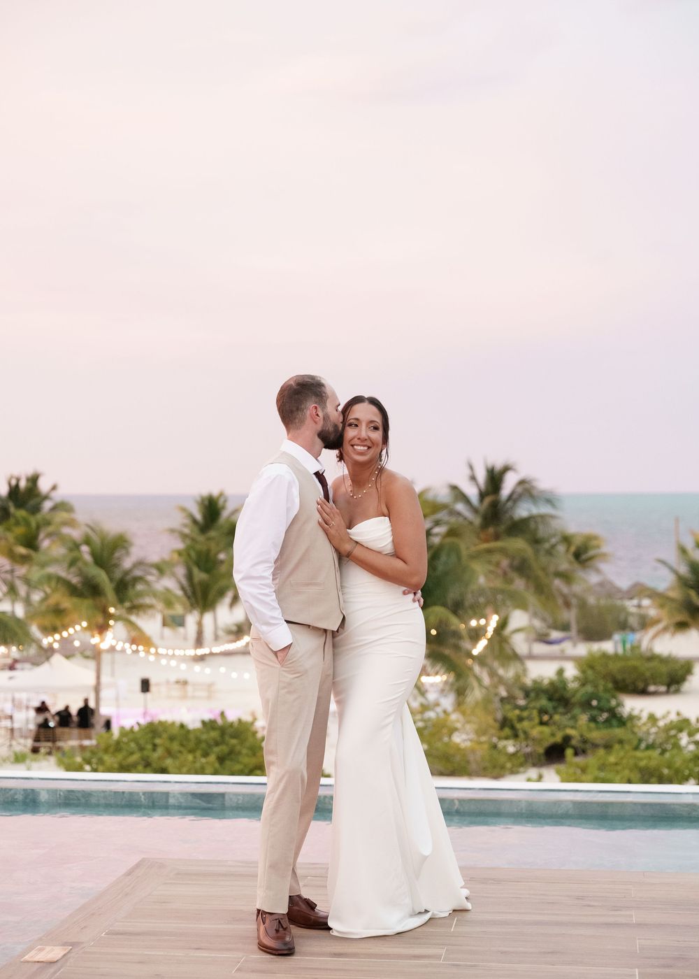 Romantic sunset wedding photos on a tropical resort terrace with palm trees and ocean views.