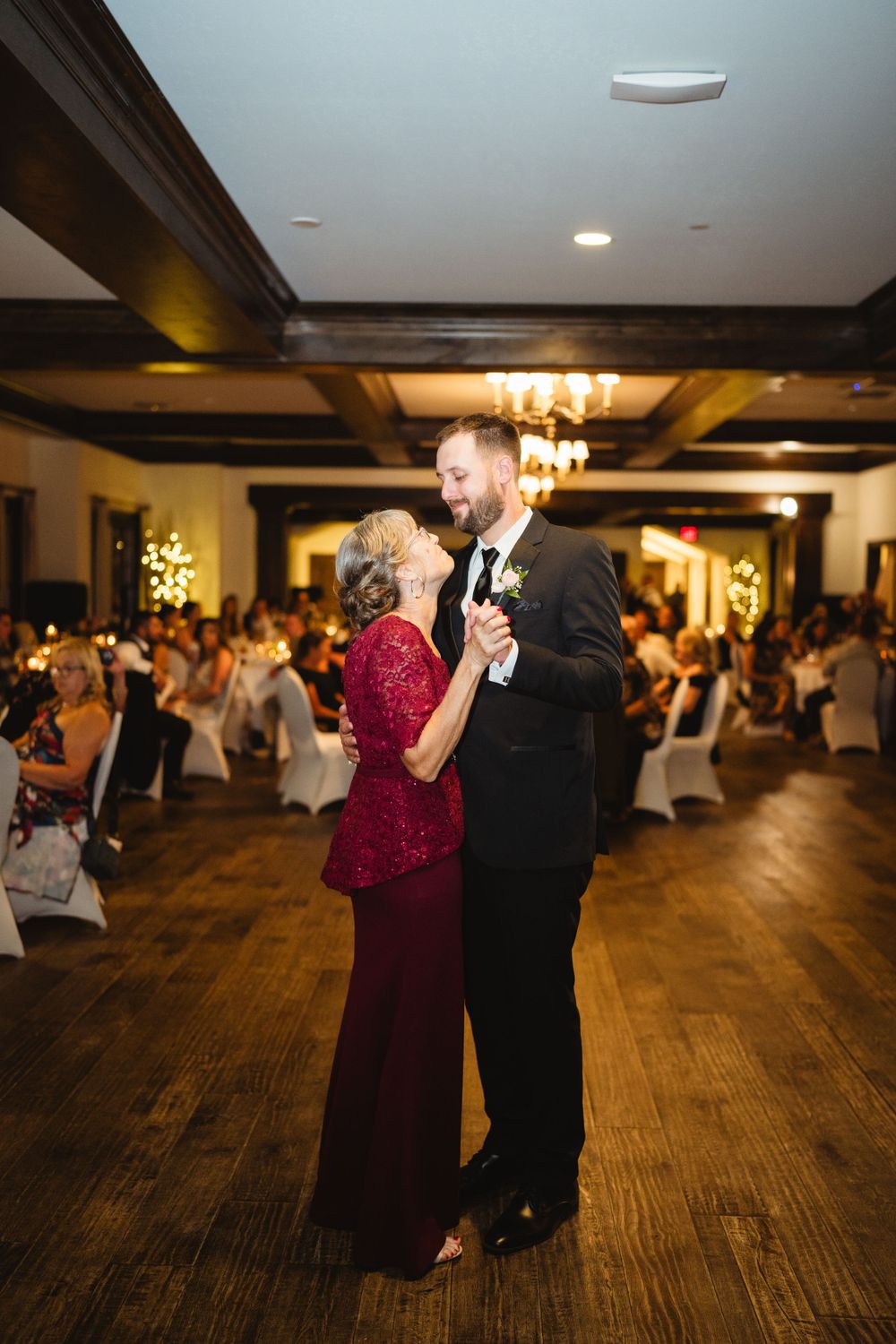 Couple dancing together at elegant wedding reception with chandelier lighting.