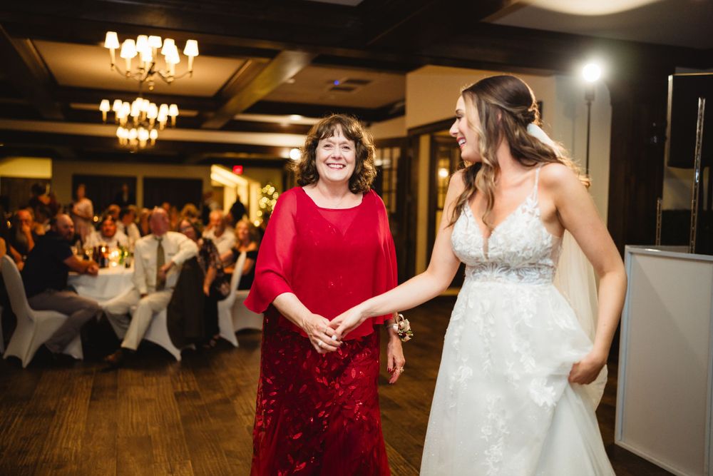 Two people dancing together at a wedding reception with chandeliers and guests in the background.