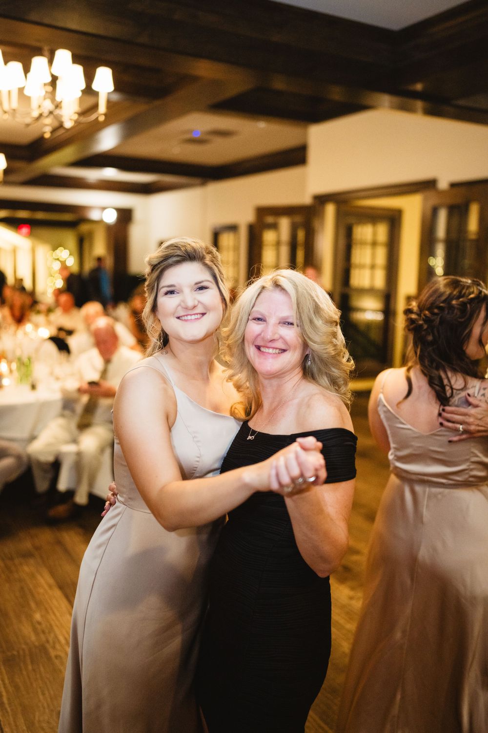 Two people sharing a joyful dance moment at an elegant indoor wedding reception.