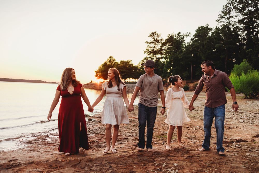 Group holds hands while walking along scenic beach at sunset.