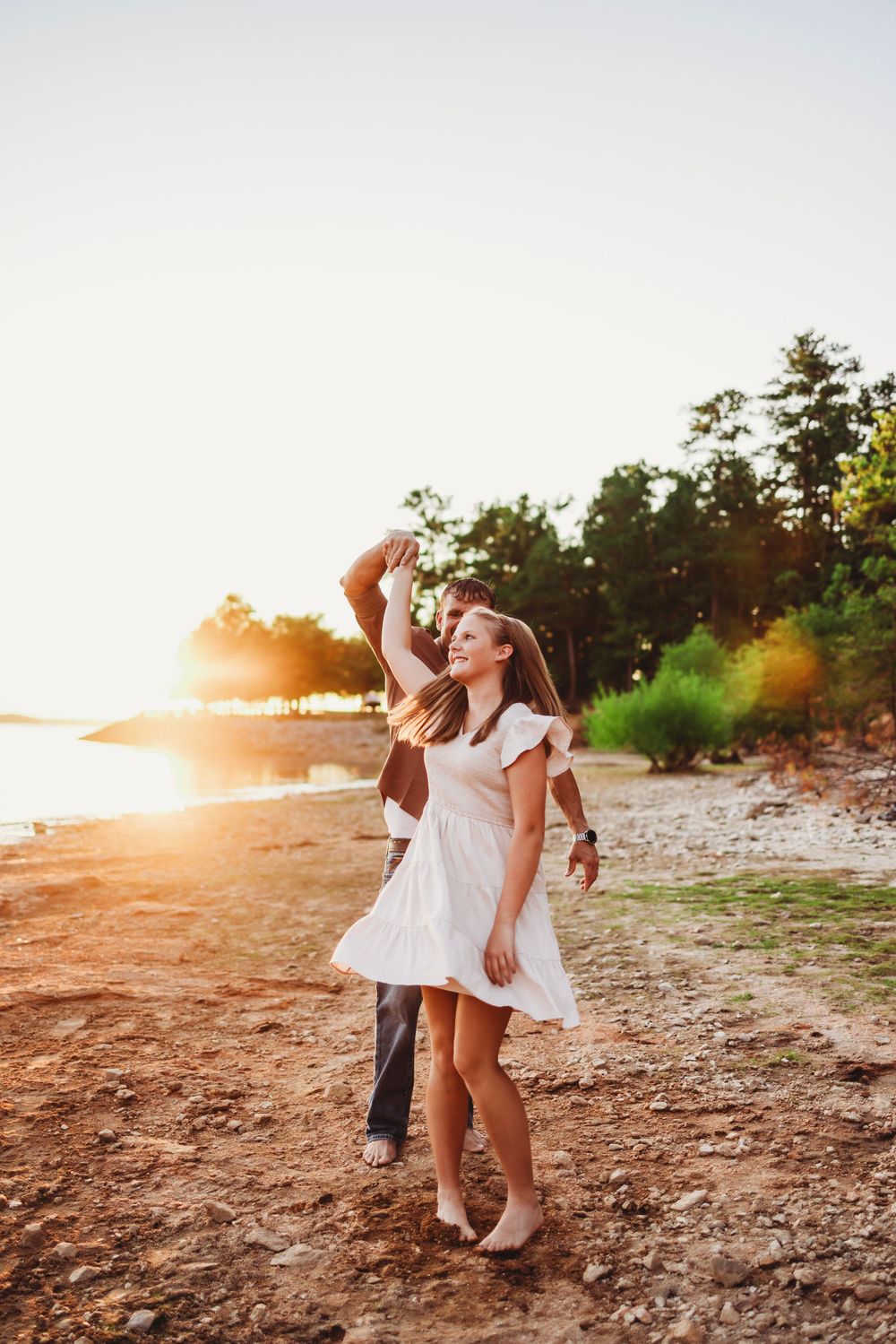 Dancing couple enjoys a romantic moment on a beach during golden hour.