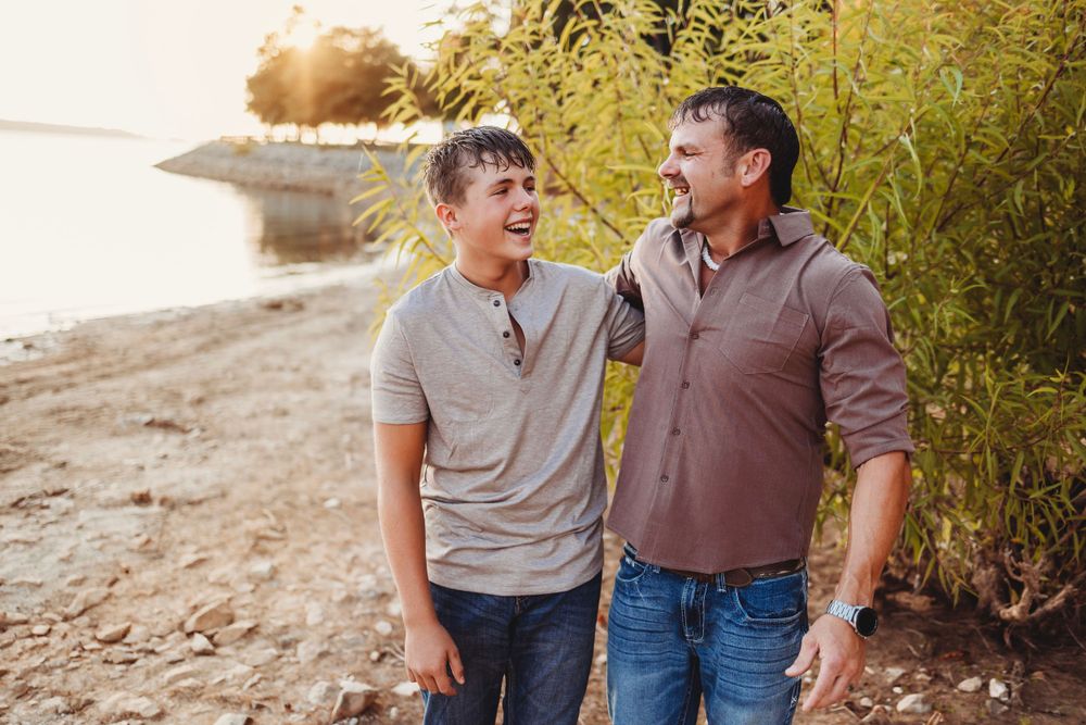 Two people sharing a joyful laugh while walking along a beach path.