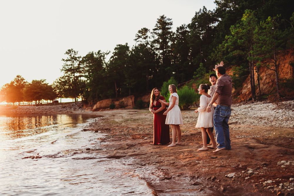 Small group enjoying sunset together on a rocky shoreline.