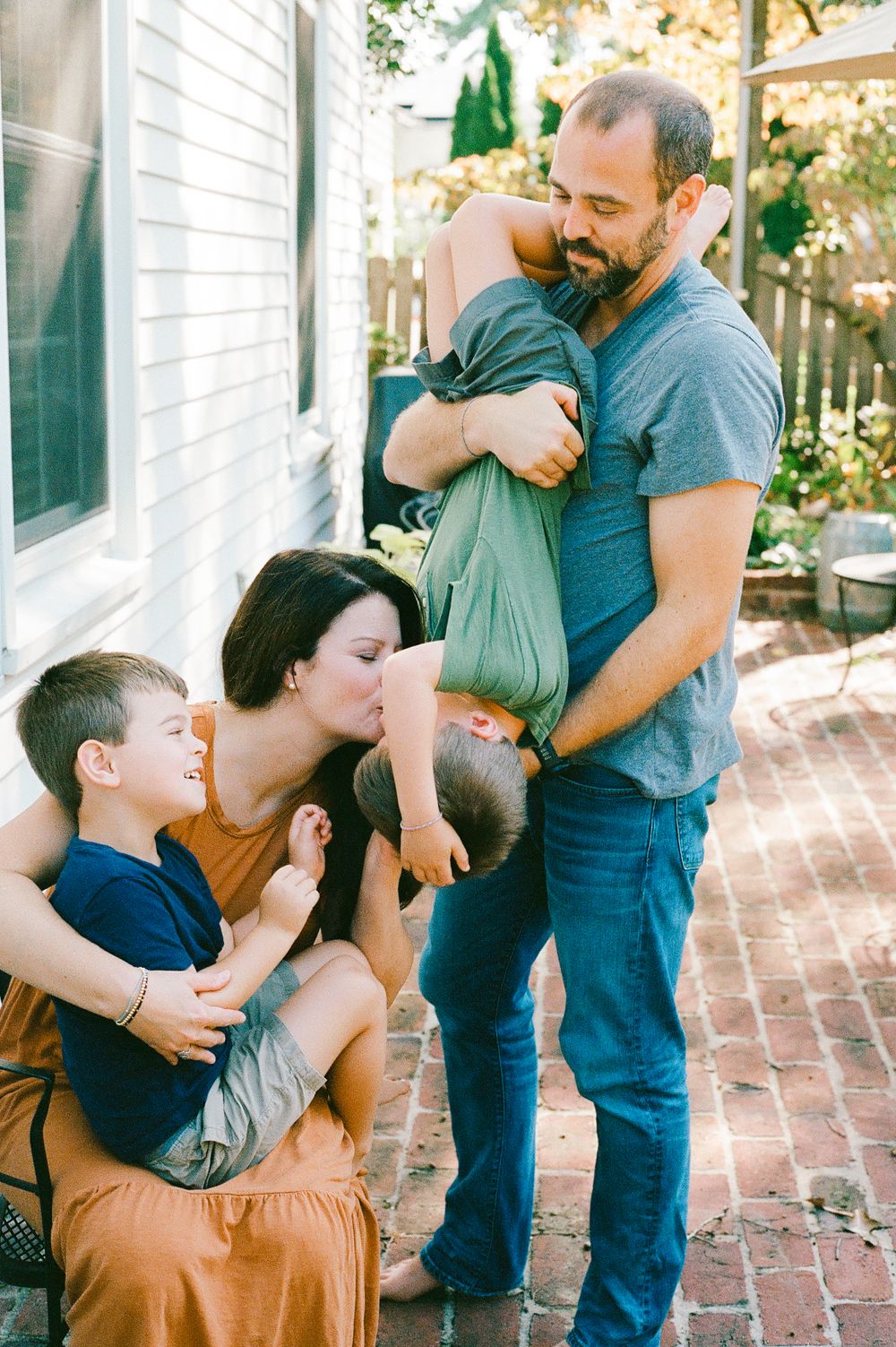 A family sharing tender moments together on a brick patio outside their home.