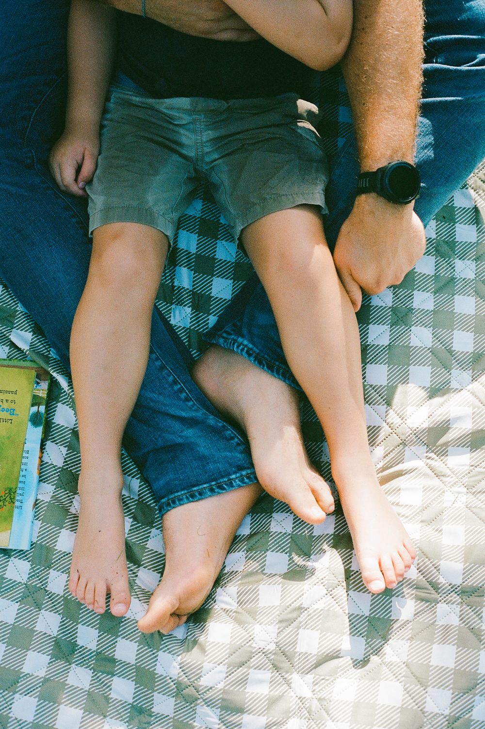 Close-up of legs resting on a checkered picnic blanket outdoors.