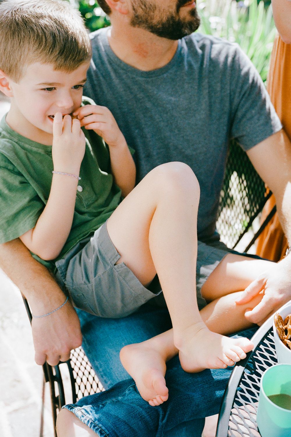 Child and adult relaxing together on patio furniture during a sunny afternoon.