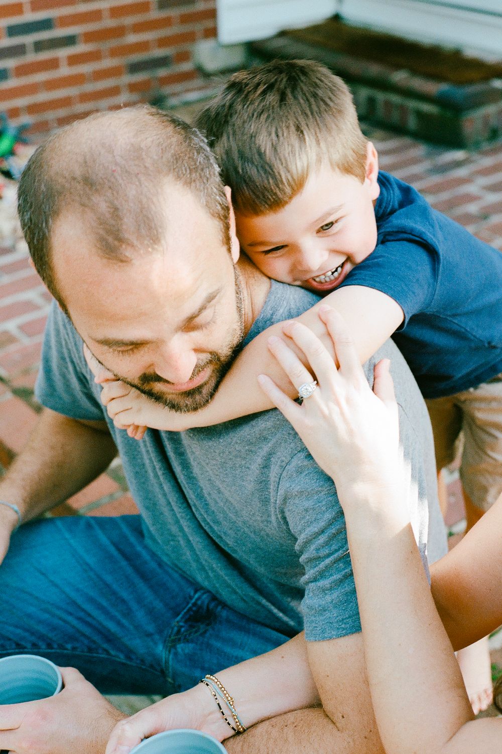 Playful moment shared between adult and child on outdoor patio.