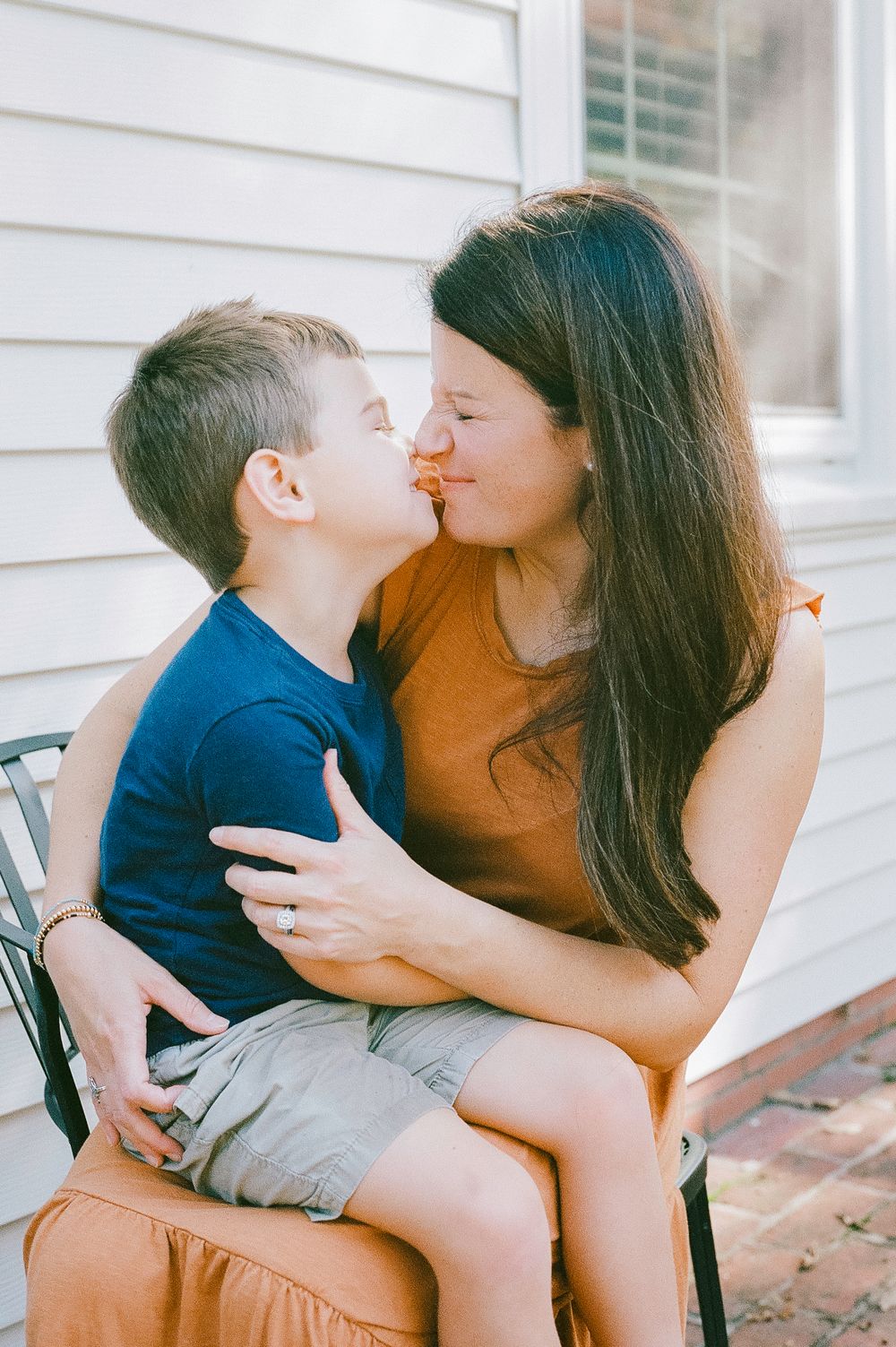 A tender moment of affection shared while sitting on an outdoor chair.
