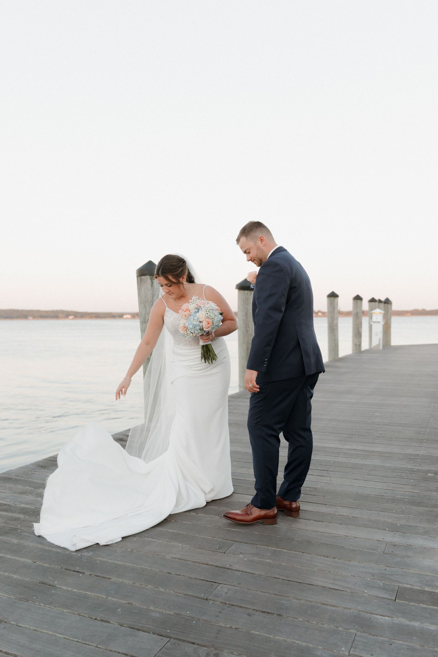 A bride and groom share a first look moment on a wooden dock by the water at sunset in Connecticut wedding venue.