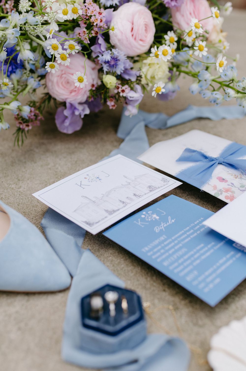 Wedding invitation suite in light blue with floral arrangements and ribbon details.