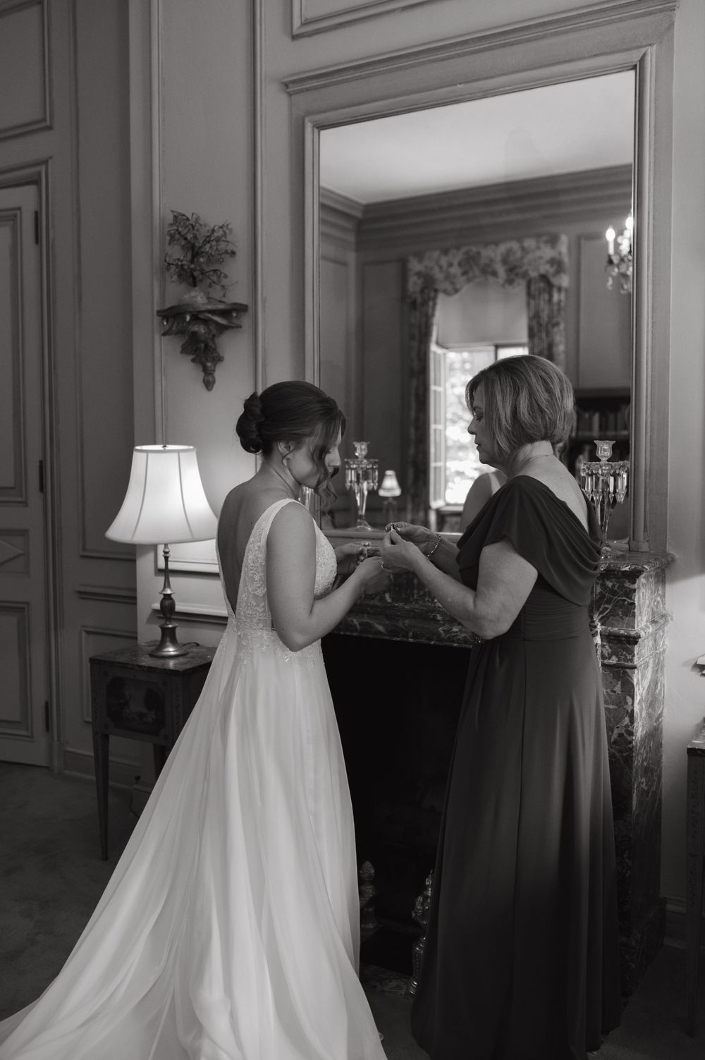 Intimate moment captured in black and white near vintage fireplace with chandelier reflection.