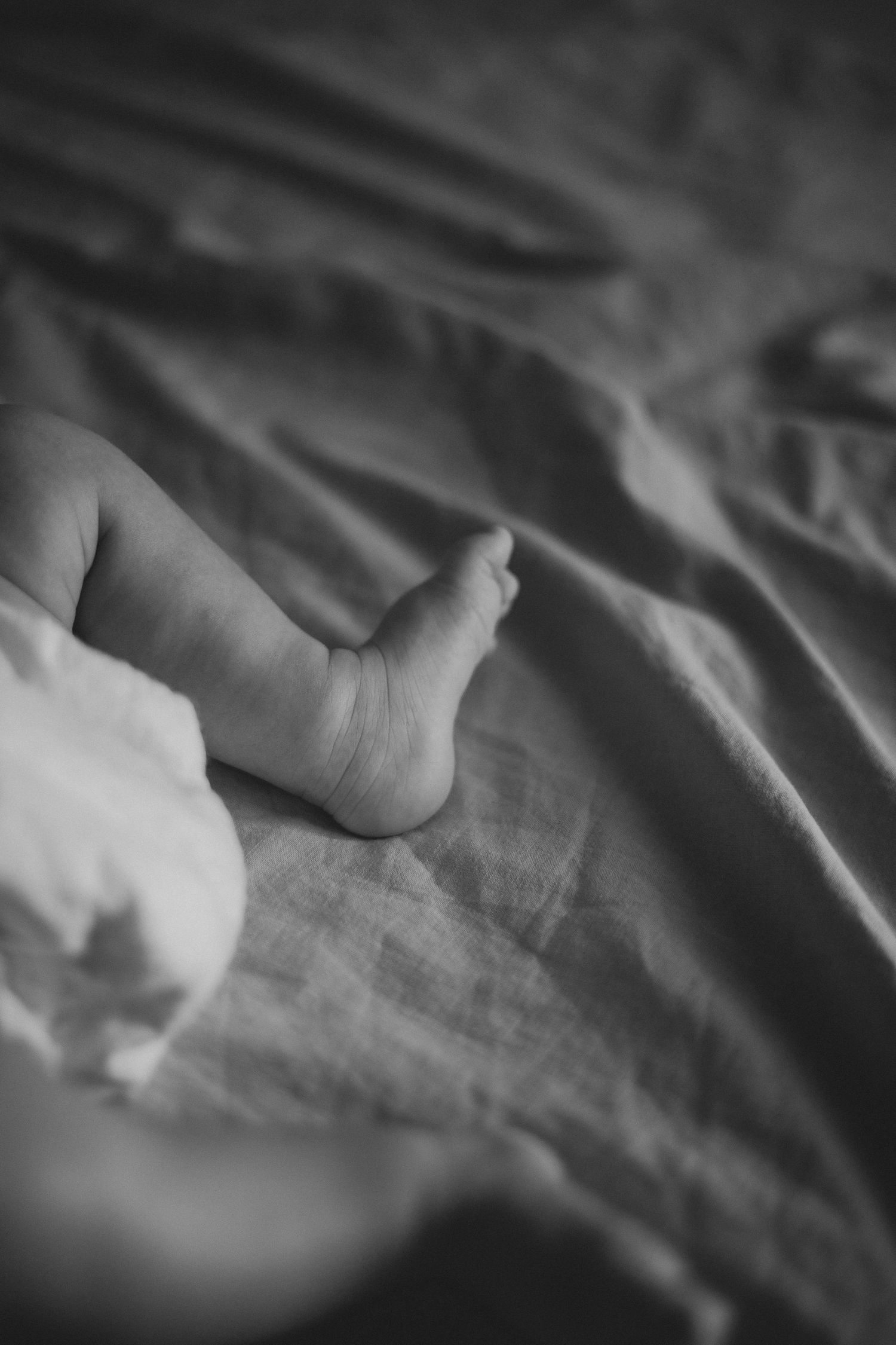 Photo en noir et blanc d'un pied de nouveau-né. Photo d'un bébé pendant une séance naissance.