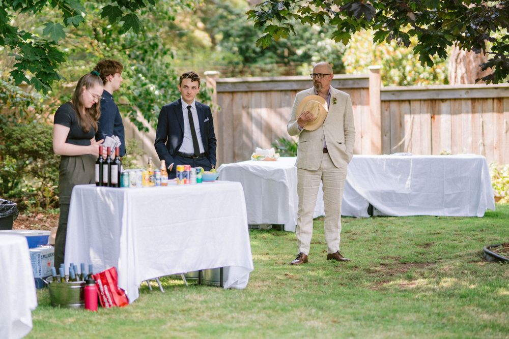 Event staff prepare drinks at a white-clothed table during an outdoor garden party.