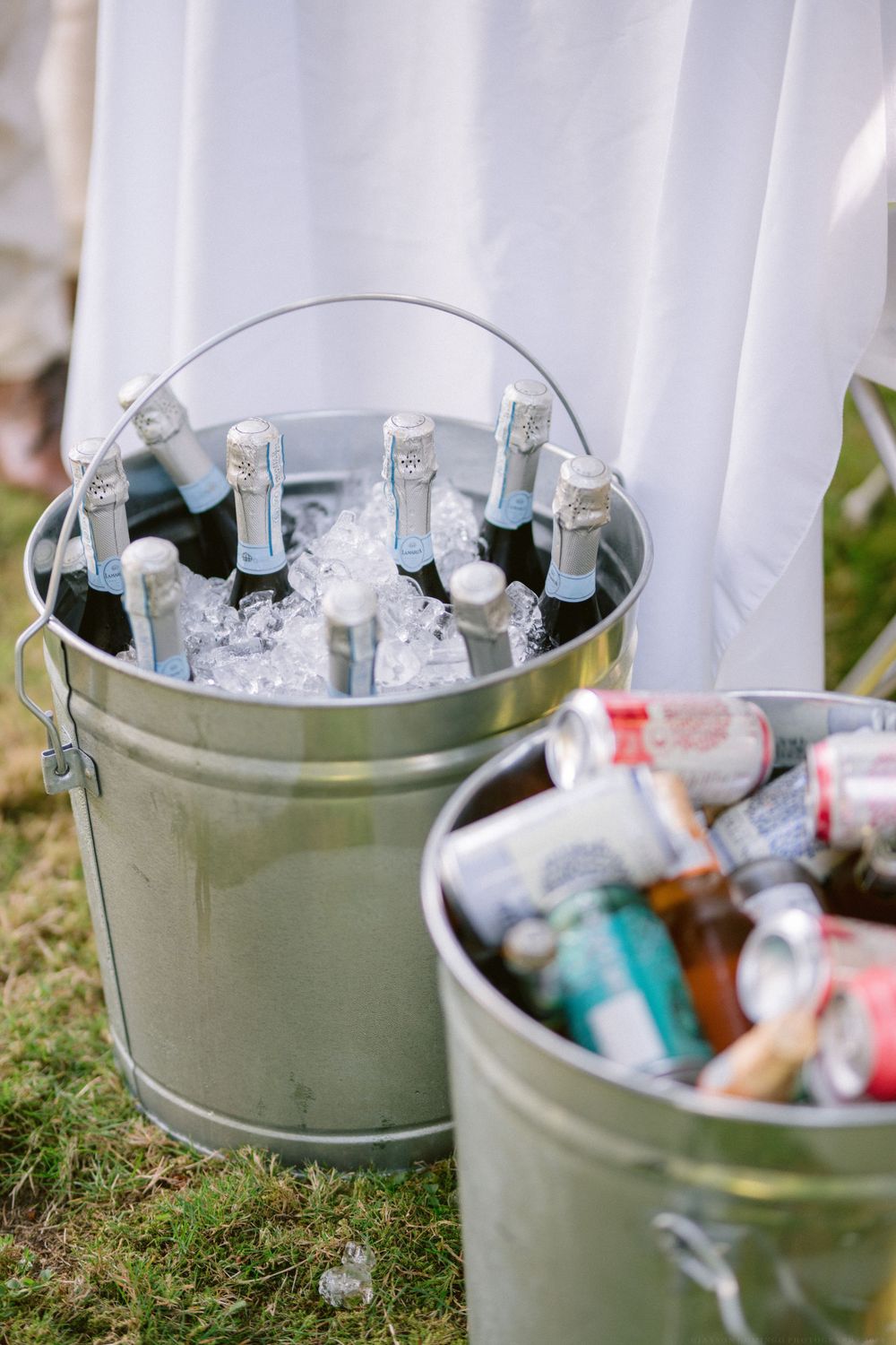 Metal buckets filled with iced beverages and drinks at an outdoor event.