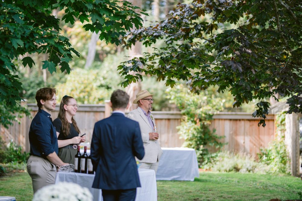 Guests mingling at an outdoor reception with tables and trees in the background.