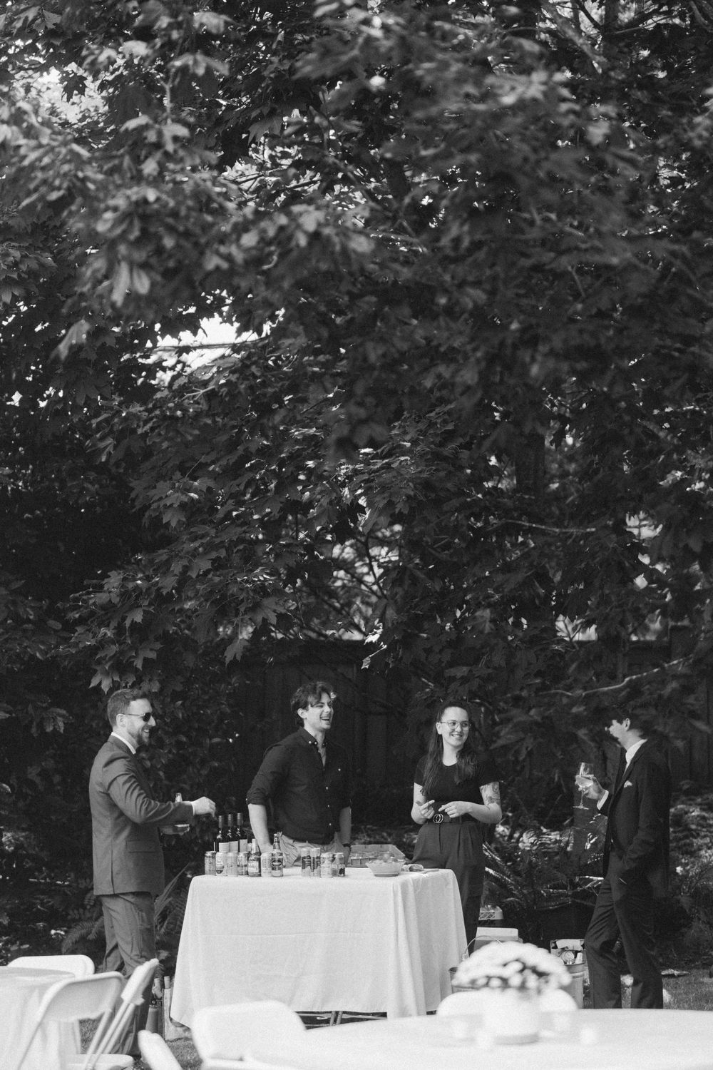 Black and white photo of people gathered around a covered table at an outdoor event.