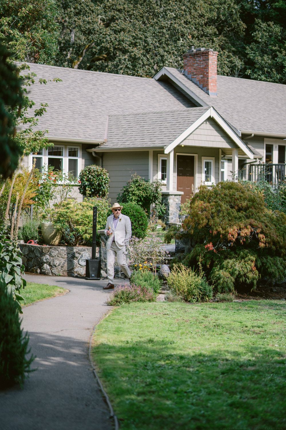 A charming craftsman bungalow with stone walkway and mature garden landscaping.