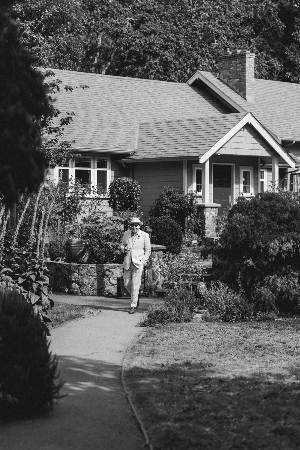 A craftsman-style house with a stone pathway and lush garden landscaping shown in black and white.