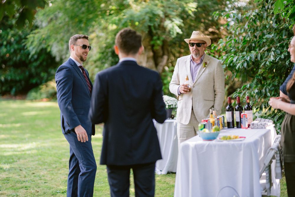 Guests mingling around a white-clothed refreshment table at an outdoor garden party.