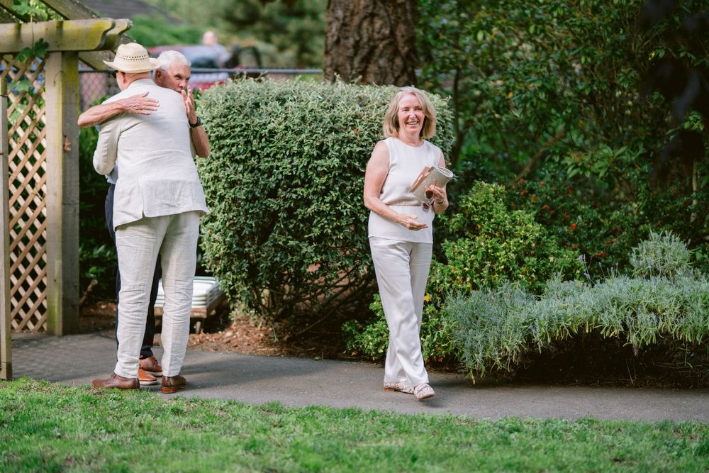 People walking along a garden path bordered by lush greenery and lattice work.