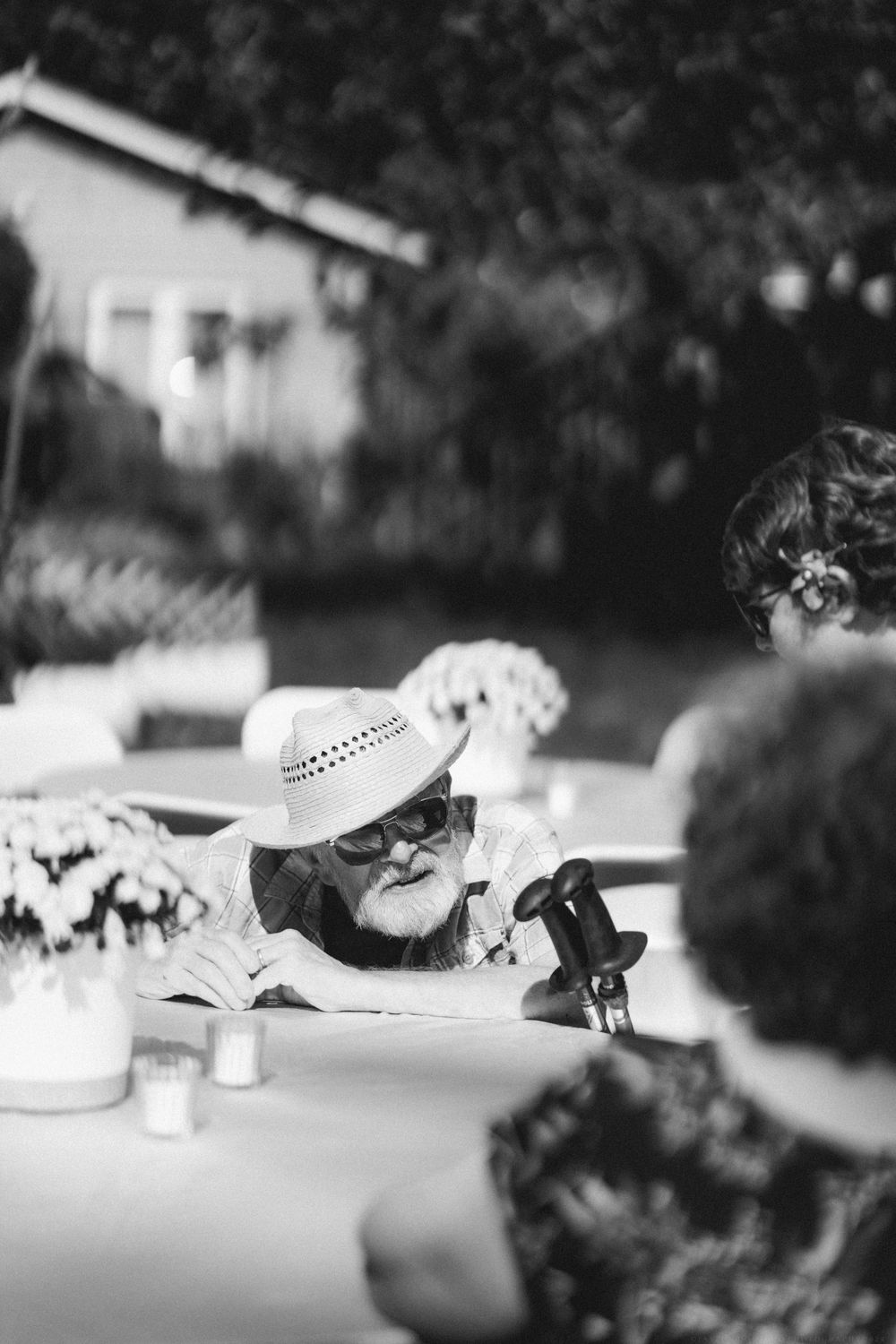 Black and white photo of guests seated at an outdoor table during a garden party.
