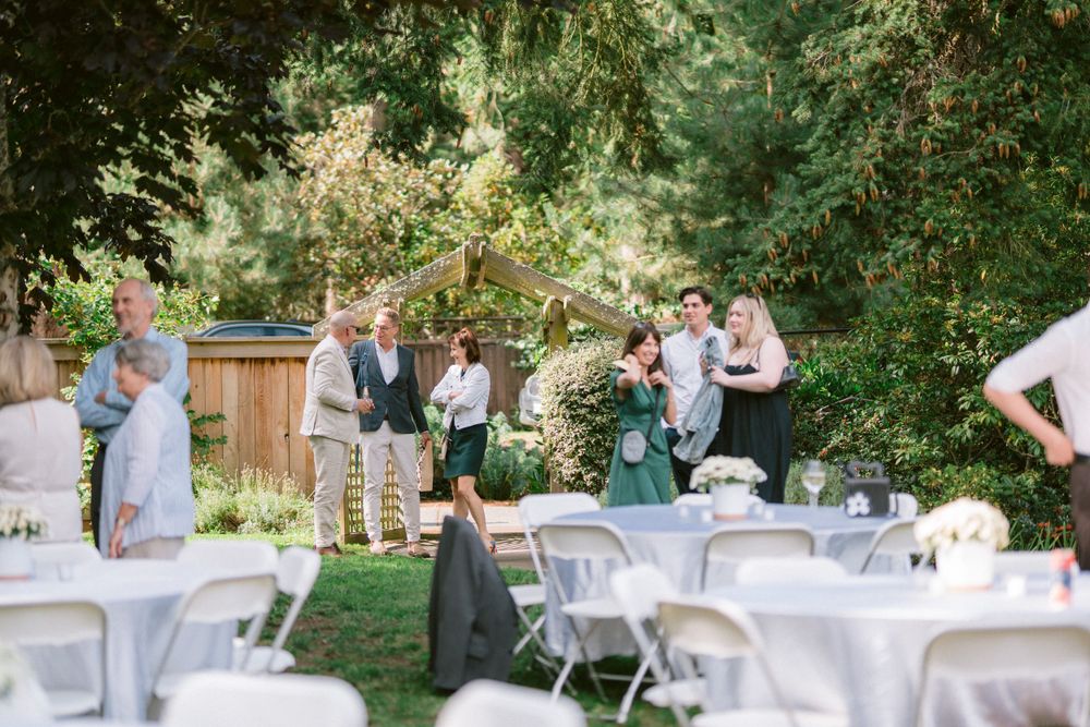 Garden party setup with white folding chairs and tables under trees.