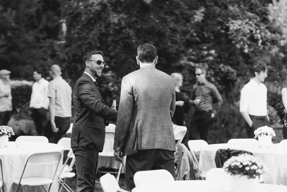 Black and white photo of guests mingling at outdoor event.