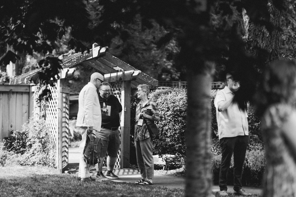 Black and white image of guests gathered near garden entrance.