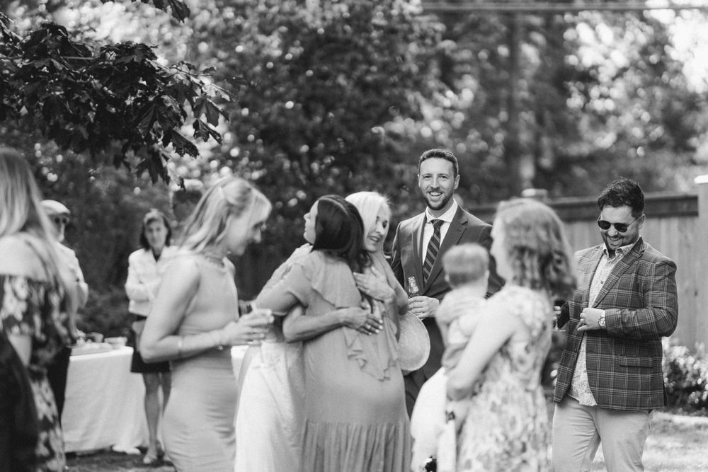Black and white photo of guests socializing at outdoor garden party reception.