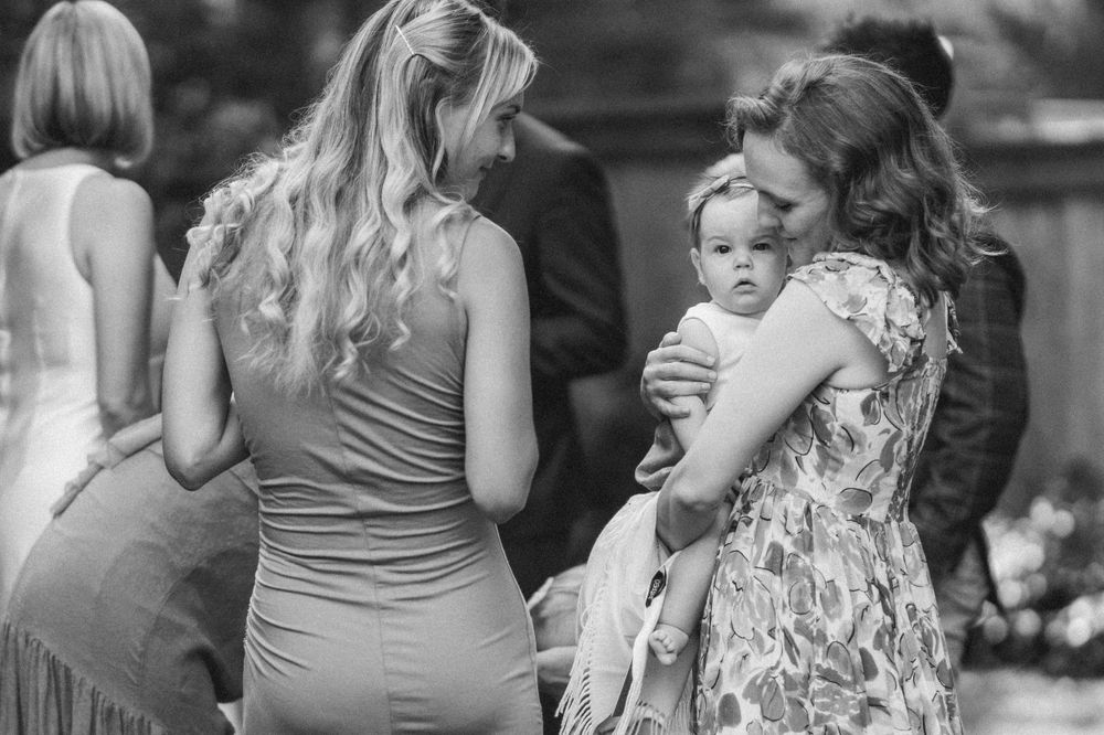 Black and white candid photo of guests chatting at outdoor social gathering.