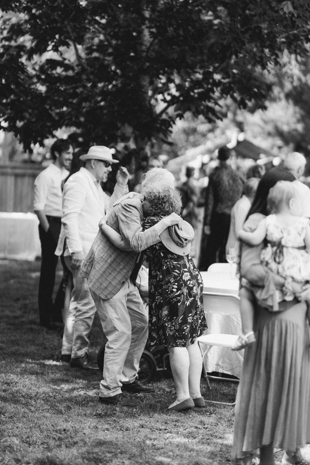 Black and white photo of guests embracing at casual outdoor garden party.