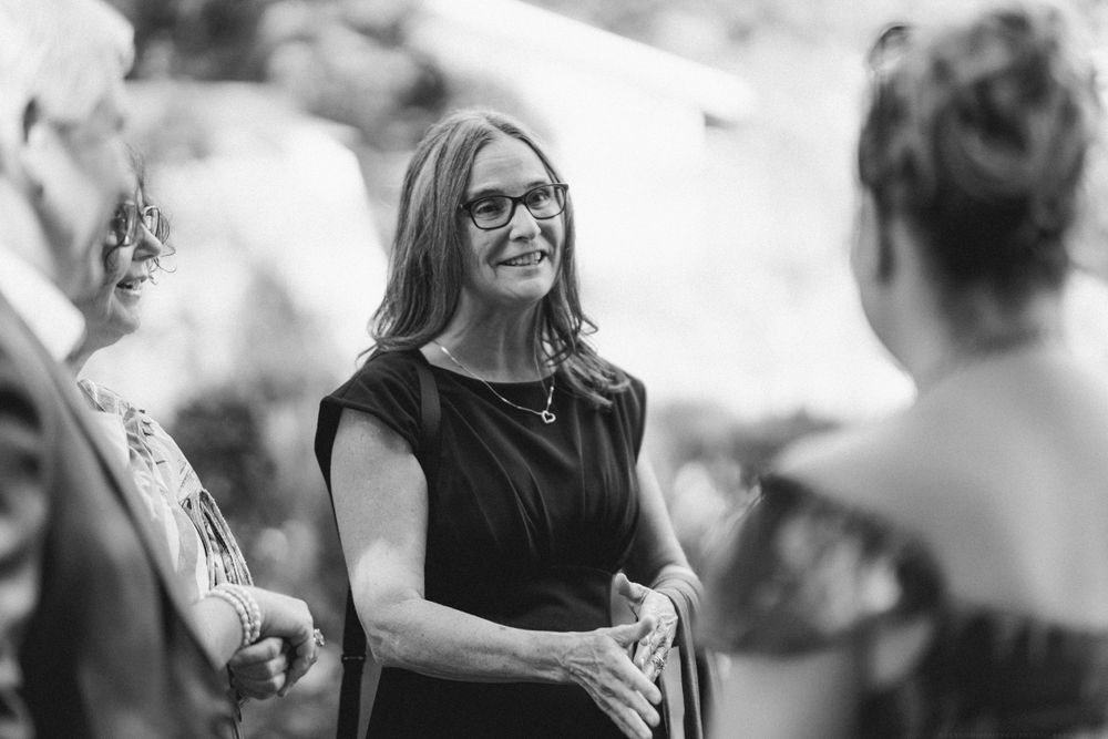 A casual conversation between guests at an outdoor social gathering.