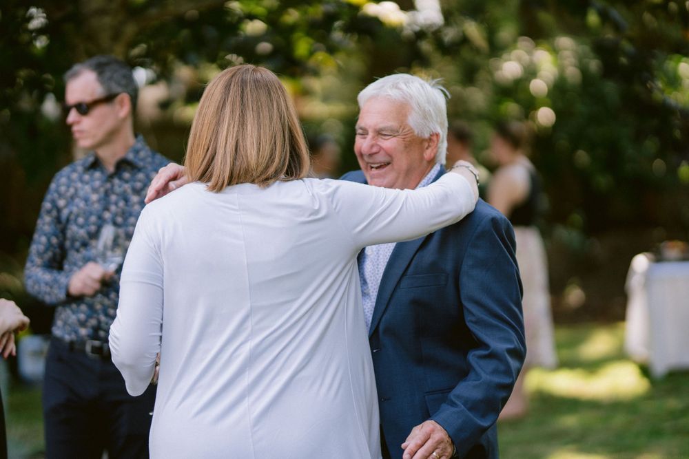 Warm embrace shared between guests at an outdoor summer celebration.