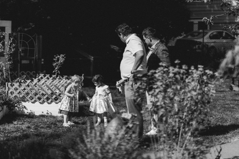 A vintage black and white photo shows people standing near a garden fence.