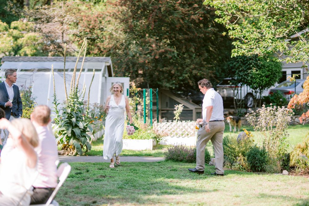 Candid moment at backyard garden party with guests mingling around white tables and chairs.