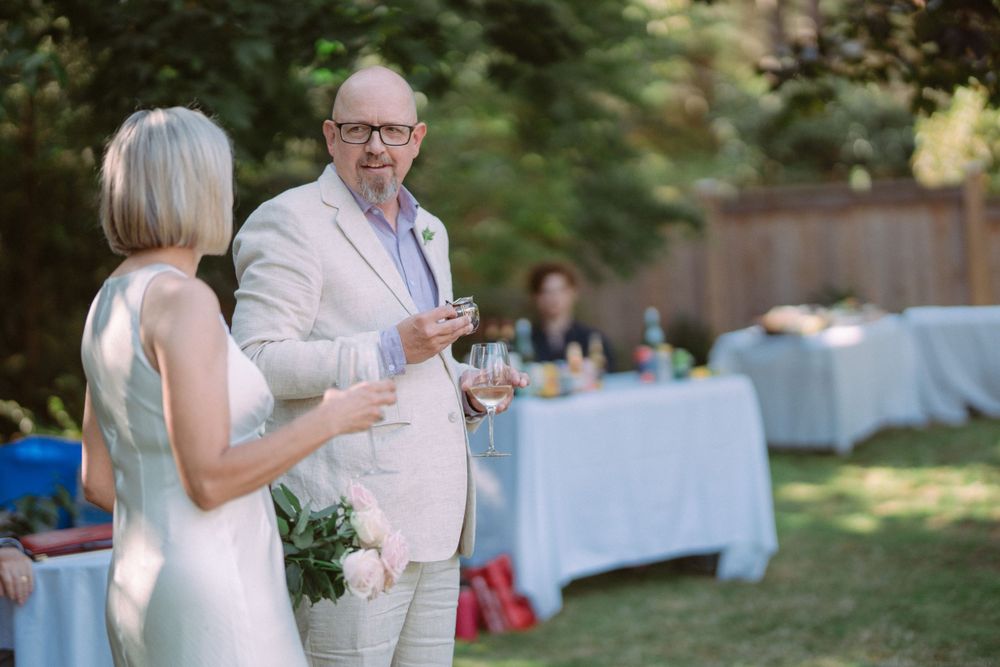Elegant outdoor garden party with guests mingling near tables draped in light blue linens.