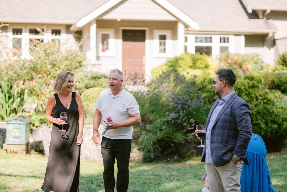 Casual outdoor gathering in front of craftsman style house with landscaped garden.