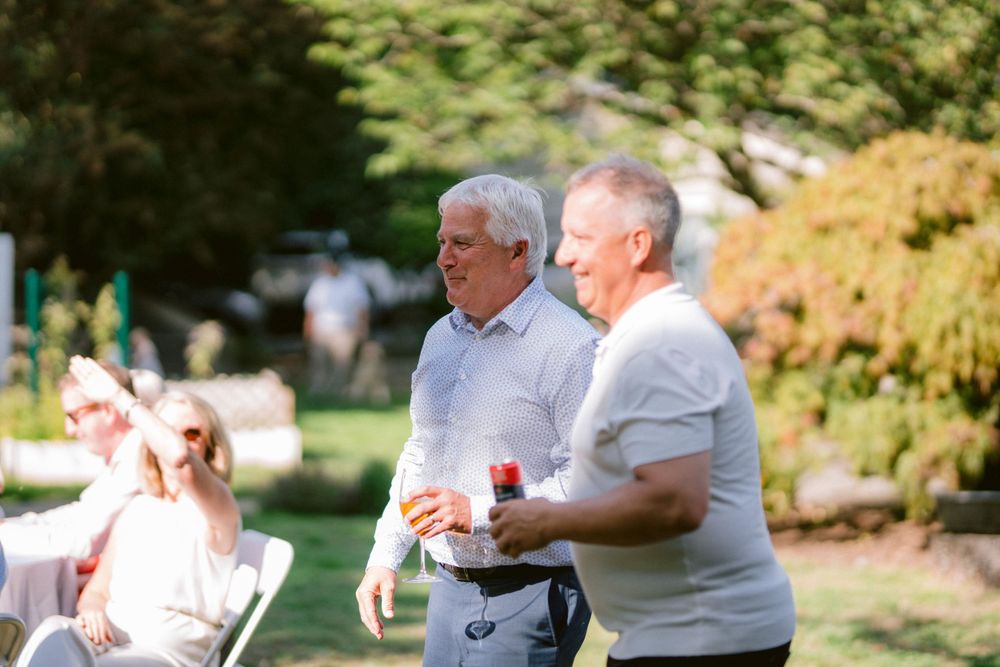 Two people chatting while standing on a sunny lawn during an outdoor social gathering.