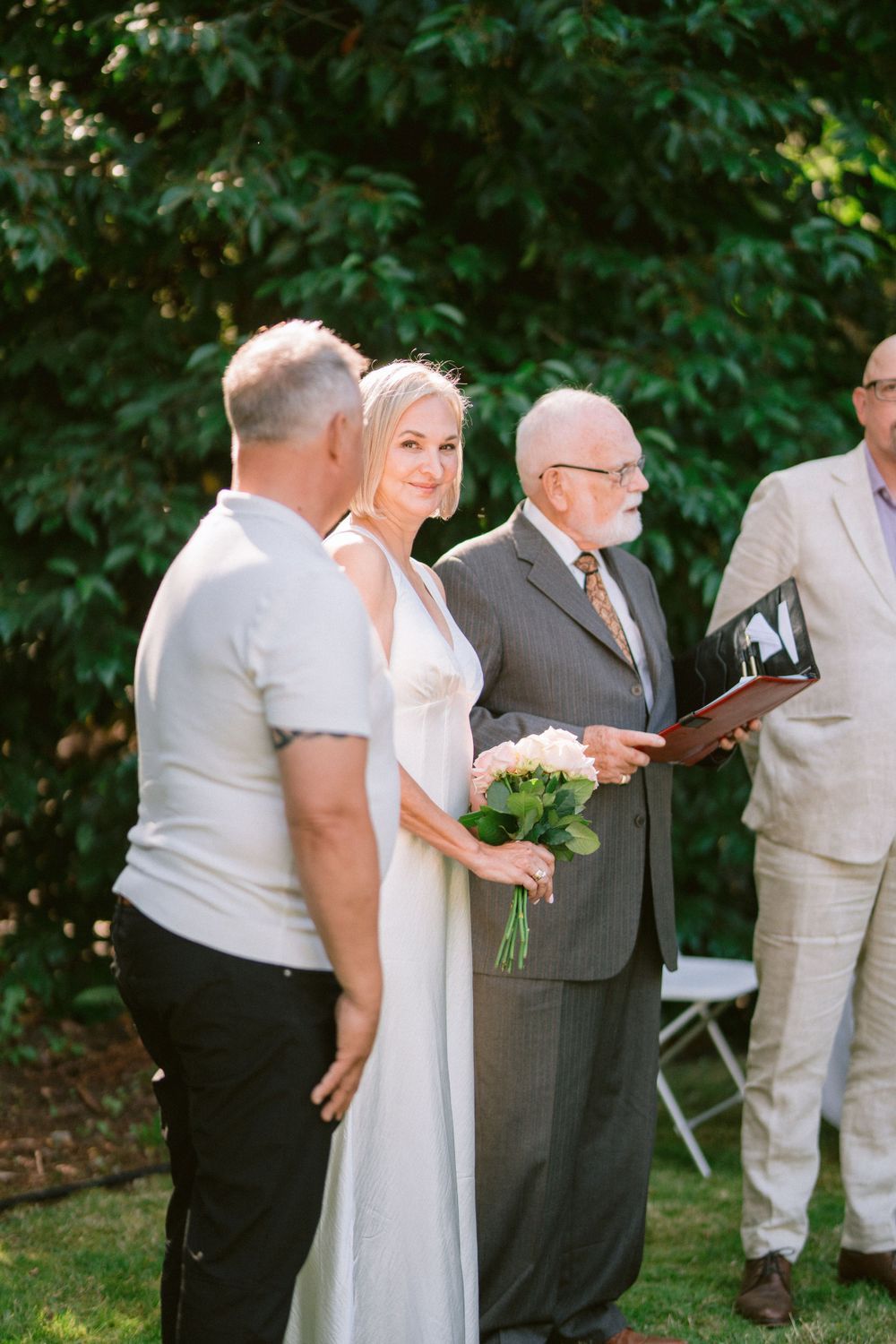 A wedding ceremony in progress in a lush garden setting with participants standing.