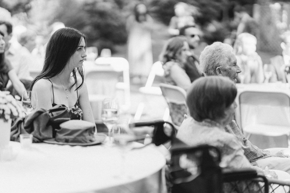 Black and white photo of guests seated at round tables during an outdoor reception.