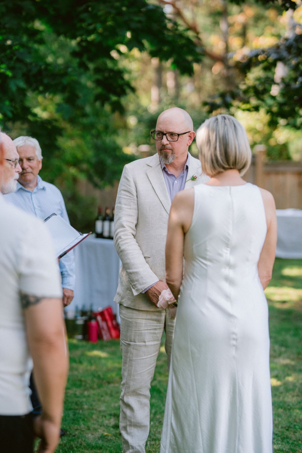 An outdoor wedding ceremony taking place in a backyard garden setting.