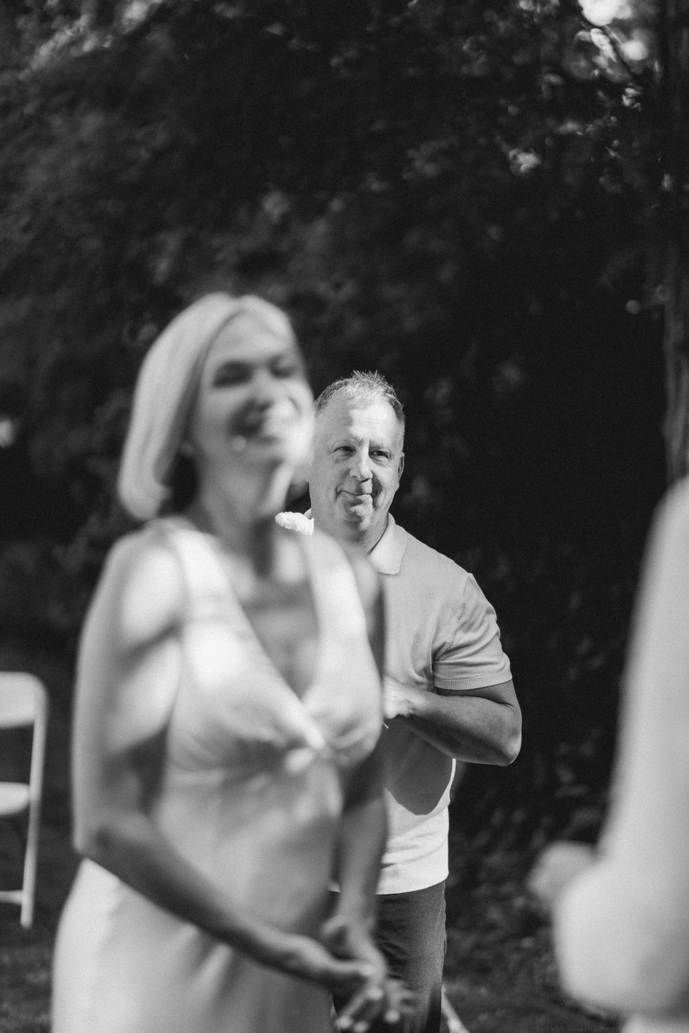 Black and white photo of a wedding ceremony moment in an outdoor garden setting.
